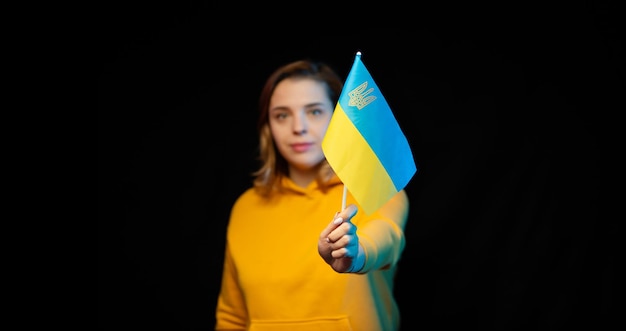 Ukraine national flag Beautiful ukrainian girl with government flag on a stick in her hands on black background Symbol of Ukrainian statehood