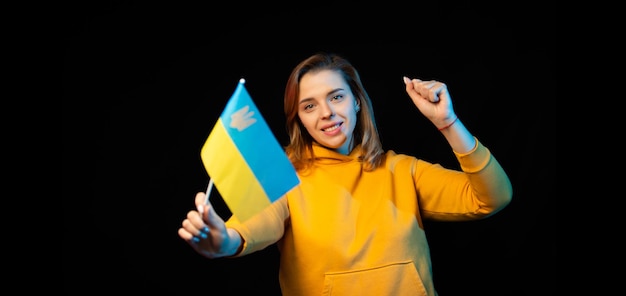 Ukraine national flag Beautiful ukrainian girl with government flag on a stick in her hands on black background Symbol of Ukrainian statehood