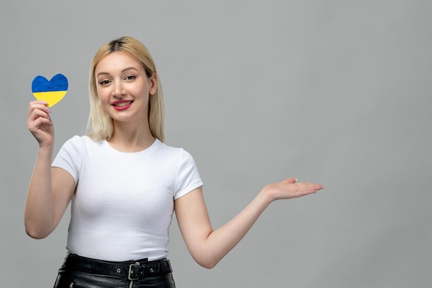 Ukraine russian conflict blonde cute girl holding ukrainian heart waving hands