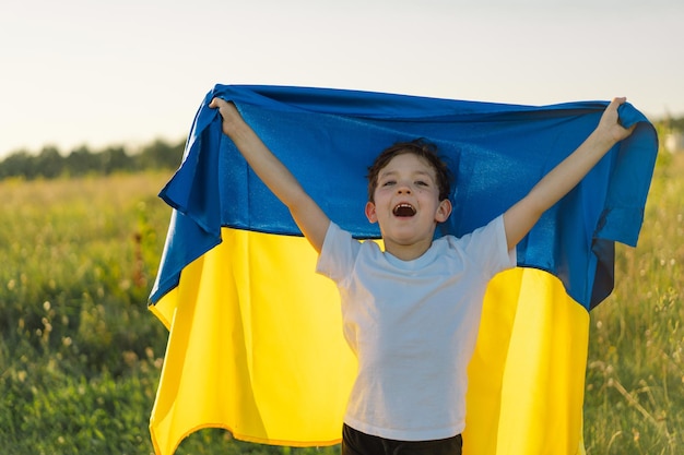 Festa dell'indipendenza dell'ucraina ragazzo bambino ucraino in maglietta bianca con bandiera gialla e blu dell'ucraina nel campo bandiera dell'ucraina giornata della costituzione stand con l'ucraina salva l'ucraina