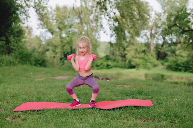 天使のような白い髪のウクライナの美しい7歳の女の子はフィットネスに従事しています