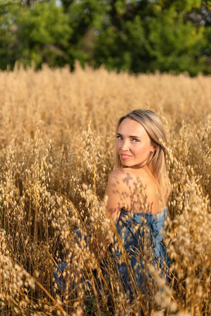 Ukrainian beautiful woman in a blue dress in a yellow wheat field