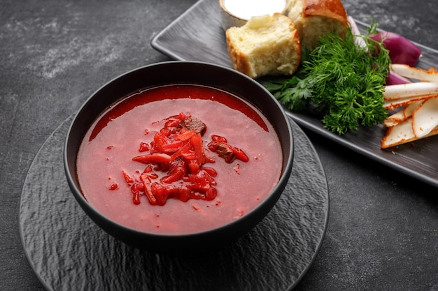 Ukrainian borscht with donuts sour cream lard and dill on a dark background