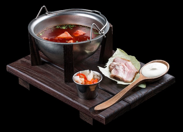 Photo ukrainian borscht with sour cream bacon and spicy snacks on a wooden board on dark background