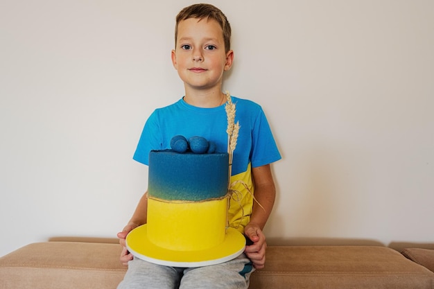 Ukrainian boy kid celebrating birthday holding big cake with flag of Ukraine