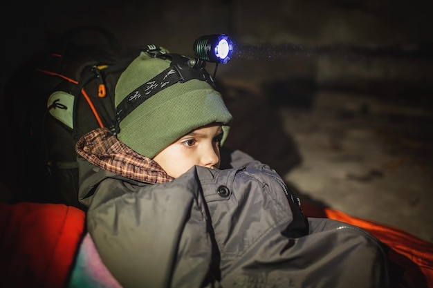 Ukrainian boy with headlamp lay in bomb shelter and waits for end of airstrike of russian invaders