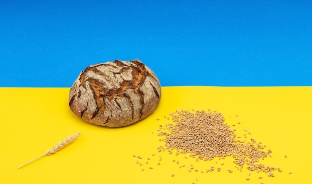 Ukrainian bread and grains of wheat on the background of the flag of Ukraine