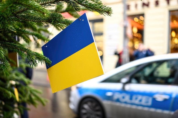 Ukrainian flag on a christmas tree against germany police car and city traffic