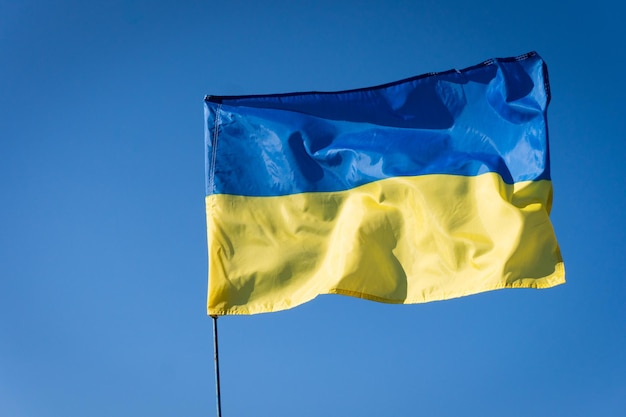 Ukrainian flag on a flagpole blue sky background