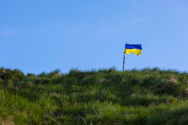 The Ukrainian flag is on a hill rises above the horizon against the background of the blue sky