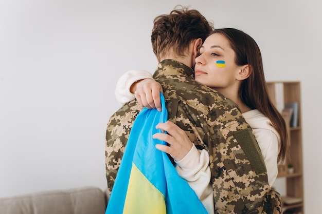 Premium Photo A ukrainian girl hugs and holds a yellow and blue flag of a military man in uniform and says goodbye to picture