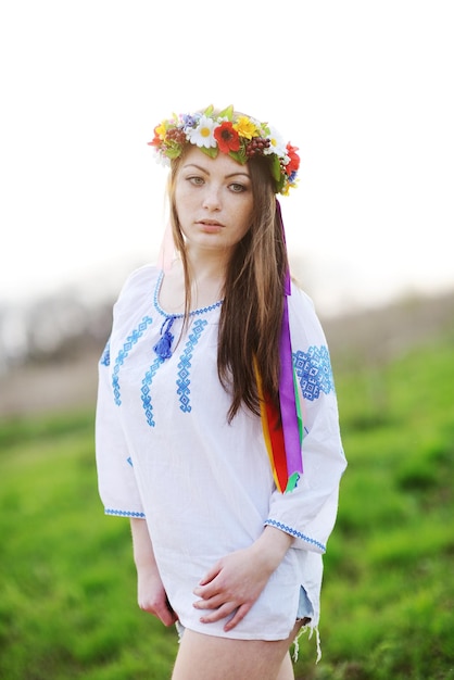 Foto ragazza ucraina con una maglietta e una corona di fiori e nastri in testa su uno sfondo di g verde