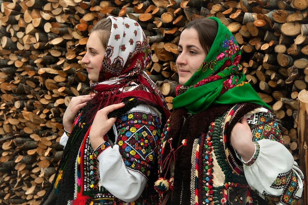 Ukrainian girls in authentic Hutsul costumes against a background of firewood