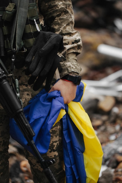 Ukrainian military woman with the Ukrainian flag in her hands on the background of an exploded house