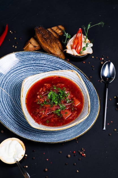 Ukrainian national dish borsch with dark bread and garlic on a dark surface. top view