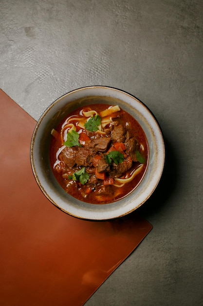 ukrainian national food borscht with meat in a plate on a gray background, top view