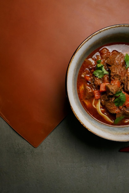 Borscht alimentare nazionale ucraino con carne in un piatto su sfondo grigio, vista dall'alto