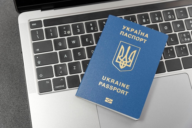 Ukrainian passport on laptop keyboard Top view Online registration for Ukrainians Online visa or immigration for citizens of Ukraine