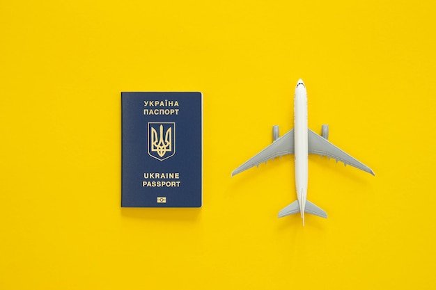 Ukrainian passport and a toy plastic plane on a yellow background top view