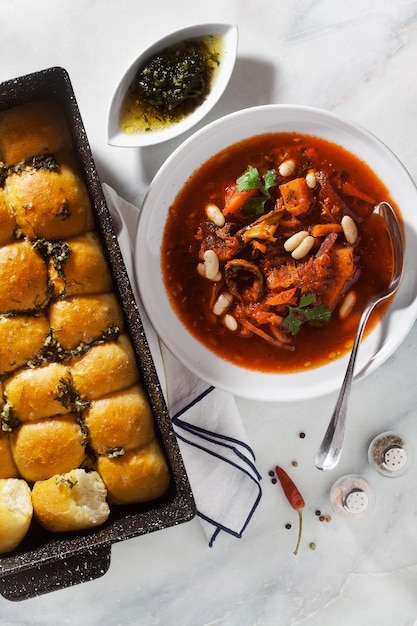 ウクライナのスープ ボルシチ マッシュルームと白豆、大理石のテーブルにパンプシキ パン