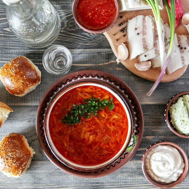 Foto zuppa ucraina bortchsh. servizio ucraino tradizionale. salo wigh aglio cipolla e panini. panna acida e salse.