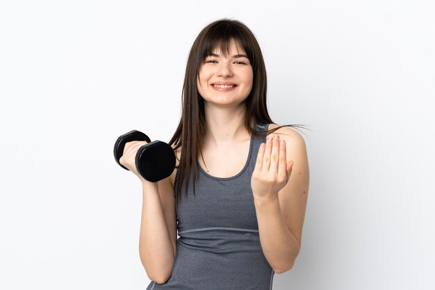 Ukrainian sport girl making weightlifting isolated on blue wall inviting to come with hand.