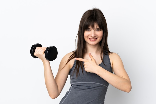 Ukrainian sport girl making weightlifting isolated on blue wall and pointing it