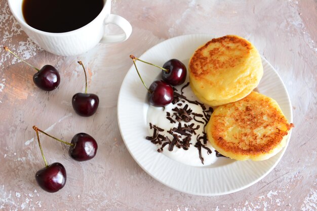 さくらんぼとチョコレートの白い皿にウクライナの syrniki