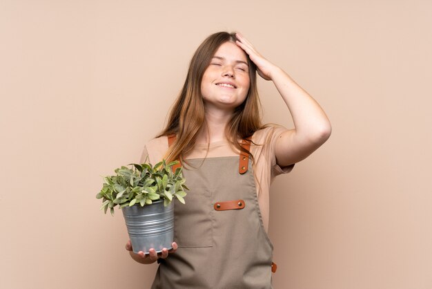 Ukrainian teenager gardener girl holding a plant laughing