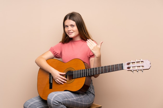 Ukrainian teenager girl with guitar inviting to come with hand. Happy that you came