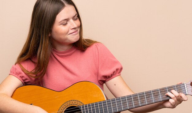 Ukrainian teenager girl with guitar over isolated