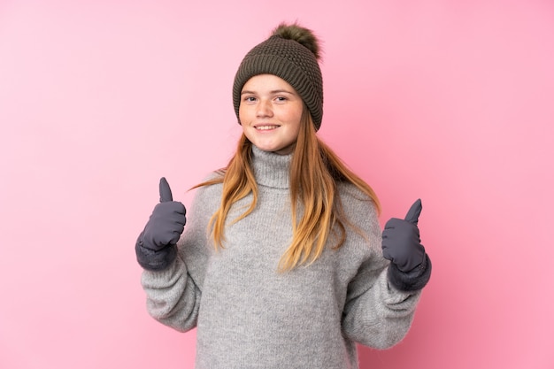 Ukrainian teenager girl with winter hat over isolated  giving a thumbs up gesture