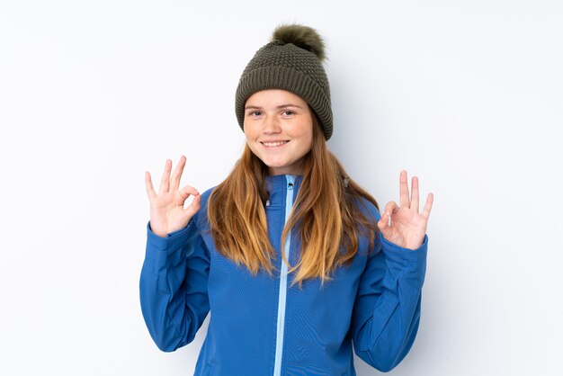 Ukrainian teenager girl with winter hat over isolated white  showing an ok sign with fingers