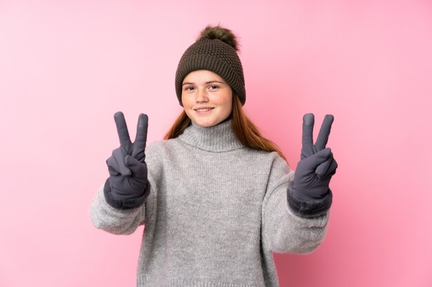 Ukrainian teenager girl with winter hat smiling and showing victory sign