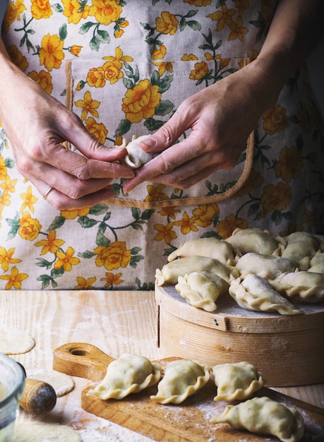 Ukrainian traditional bakery products - Making pierogies by female hands. Rustic style. Retro Photo