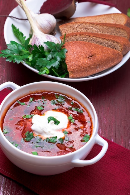 Ukrainian traditional borsch. Russian vegetarian red soup  in white bowl on red wooden .  Borscht, borshch with beet.