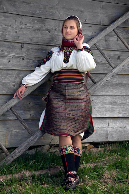 Photo ukrainian woman in an authentic hutsul costume stands near a ladder