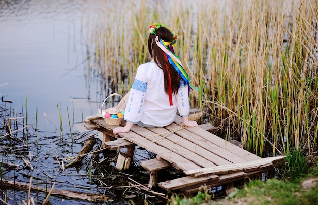 Donna ucraina in camicia che si siede vicino al fiume