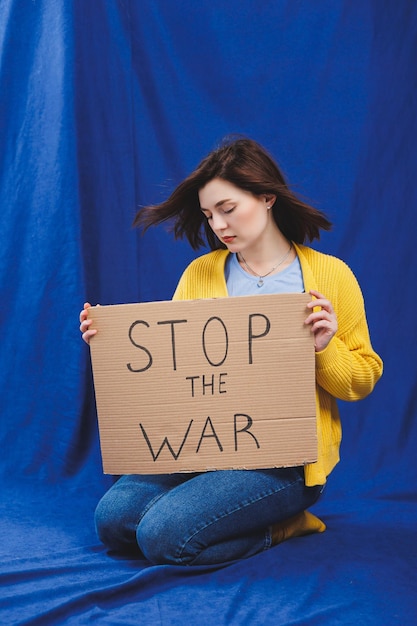 A Ukrainian woman in a yellow sweater and blue jeans with a stop the war sign Ukrainian girl suffered from the war No war