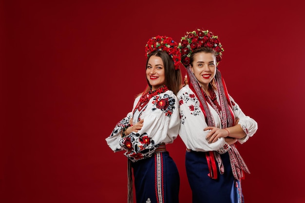 Ukrainian women in traditional ethnic clothing and floral red wreath on viva magenta studio background National embroidered dress call vyshyvanka Pray for Ukraine