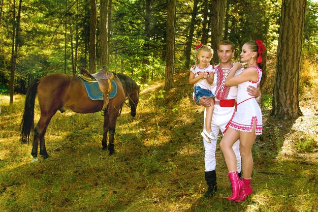 Ukrainians mom and dad and daughter in the woods with a horse