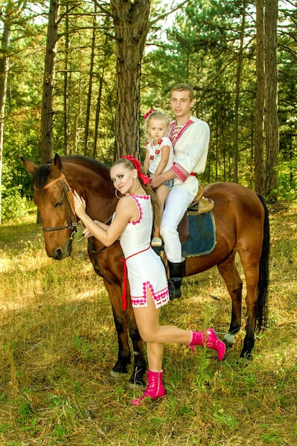 Ukrainians mom and dad and daughter in the woods with a horse