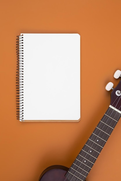 Ukulele guitar and notebook on brown background flat lay musical creativity concept copy space