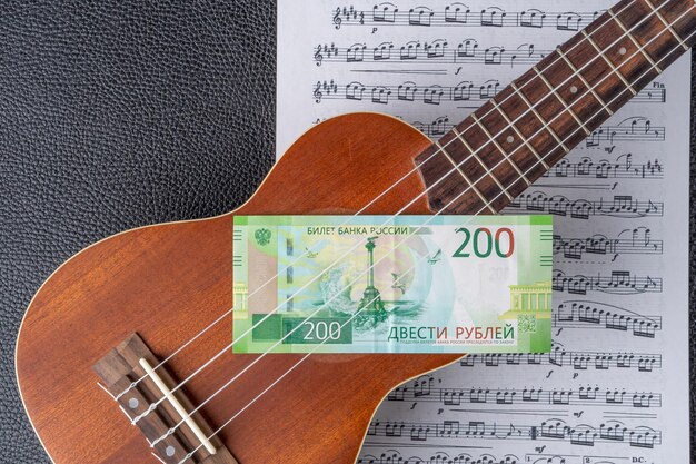 Photo a ukulele with a green bill and a note that says 200.