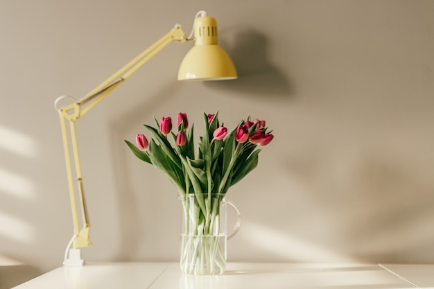 ulips in vase and yellow lamp in home interior