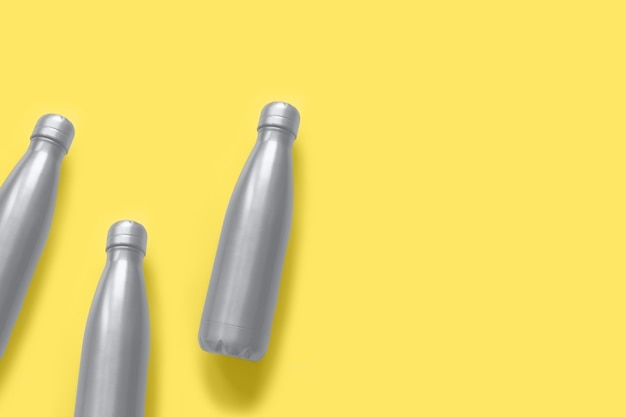 Ultimate gray color reusable metallic water bottles on an illuminating yellow background