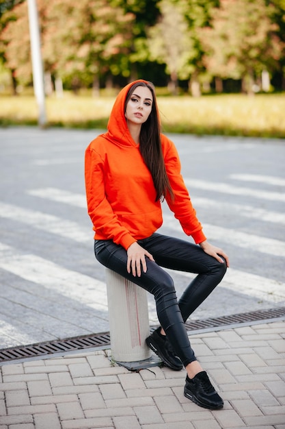 Ultra-modeconcept. Jonge vrouw van mode oranje trui dragen en poseren over oranje bakstenen stedelijke achtergrond. Street Style. zakenvrouw. modieuze accessoires.