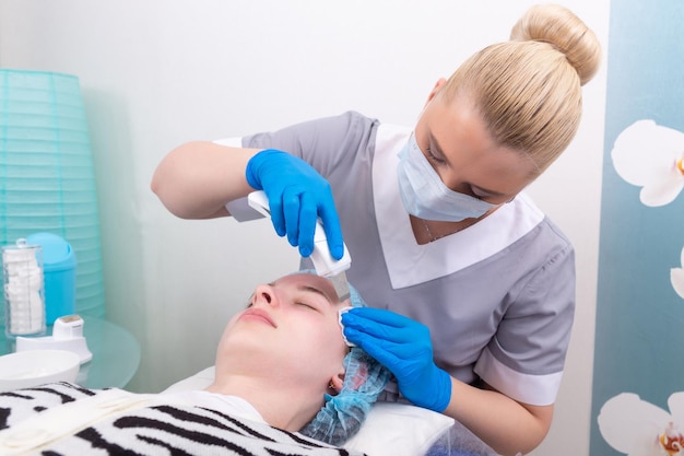 Peeling facciale a ultrasuoni giovane donna che ottiene pelle a buccia ultrasonica con scrubber per la pelle presso la clinica di cosmetologia