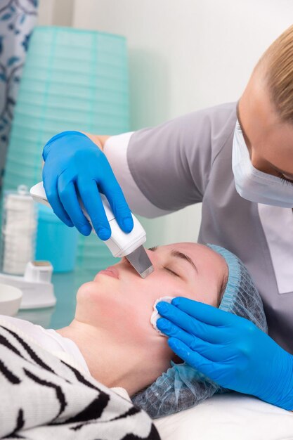 Ультразвуковой пилинг лица Молодая женщина получает ультразвуковой пилинг кожи с помощью скруббера в косметологической клинике