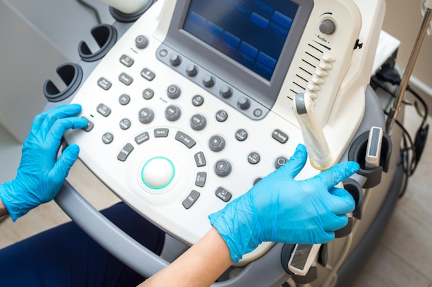 Ultrasound machine and hands of a gynecologist closeup Condom ultrasound probe for vaginal examination